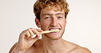 Germs, face or man brushing teeth in studio on white background for eco friendly hygiene. Portrait, care or model with space or morning routine with bamboo toothbrush, dental cleaning or oral health