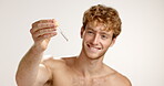 Serum, skincare and smile with man in studio for vitamin c, beauty and facial treatment. Essential oil, cosmetics and self care with person and dropper on white background for dermatology and glow