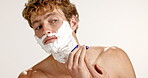 Concentration, razor and shaving with man on studio background for grooming, hair removal or hygiene. Face, foam and skincare with serious person getting ready in bathroom for morning wellness