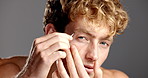 Face, grooming and man with tweezers for eyebrow, gray background and trimming for facial treatment. Hair removal, routine and person with tool for process, studio and confident with equipment