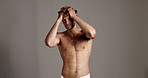 Beauty, face and hair with shirtless man in studio for masculine grooming, hygiene or skincare. Confident, fitness and muscular with bare model on gray background space for aesthetic wellness