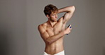 Spray, deodorant and face of man in studio for hygiene, cosmetics and armpit self care. Antiperspirant, perfume product and beauty with person on background for cleaning, grooming and body mist