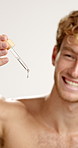 Happy man, hands and dropper with serum for skincare or vitamin C oil on a white studio background. Male person, model or smile with pipette or liquid for skin antioxidant, moisturizer or dermatology
