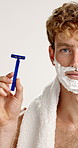 Shaver, cream and face of man in studio with grooming, epilation or self care for morning routine. Razor, health and portrait of person with shaving for hair removal treatment by white background.