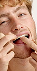 Oral care, floss and face of man in studio for hygiene, plaque removal or grooming in morning. Dental health, wellness and person with string for cleaning teeth or fresh breath by white background.