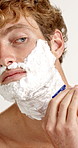 Razor, cream and man in studio with grooming, epilation or self care for morning routine with beard. Shaver, health and male person with shaving for hair removal treatment by white background.