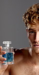 Face, cologne and man in studio, dermatology  and grooming on gray background. Portrait, shirtless and model with perfume, person and aesthetic with beauty, aroma and fragrance bottle with cosmetics