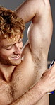 Deodorant, smile and spray with shirtless man in studio for fresh aroma, grooming or hygiene. Body, cologne and underarm smell with happy model on gray background to apply fragrance for self care