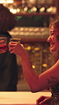 Happy people, drinking and nightclub with bartender for alcohol, social interaction or party. Group, friends or customers with glass or cheers for bonding, event or night out together at bar counter