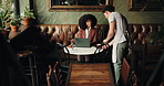 Cafe, waiter and serving with customer on laptop for order, beverage or purchase in restaurant. Woman, barista or man with caffeine or drink for hospitality, accommodation or service in coffee shop