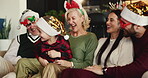 Happy family, christmas and playing with child on sofa for festive holiday or celebration in home. Grandparents, parents and hug with playful kid or santa hat for december weekend or bonding together