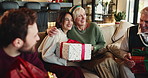Happy family, christmas and hug with gift on sofa for surprise or festive celebration in home. Excited, group or bonding with box, smile or embrace for giving, holiday or presents together in house