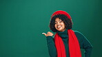 Christmas, pointing and space with face of woman in studio for festive advertising or marketing. Announcement, notification and promotion with happy African person on green background for winter sale