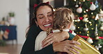 Christmas, hug or present with mother with daughter in living room of home for festive celebration. December, gift or thank you with girl child and single parent embracing in apartment for holidays