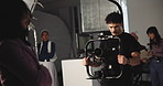 Director, videographer and video camera with actress for commercial or production studio on set. Man, producer and filming team with cast or actor for recording behind scene, script or documentary