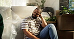 Thinking, man and sad for eviction, boxes and stress for relocation, living room and worry in house. Contemplating, tenant and black person with anxiety for move, depressed or reflection in apartment