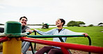 Happy people, friends or spinning in playground on roundabout for fun break or adrenaline in nature. Excited, man and woman with smile in joy on carousel for energy, freedom or playing together