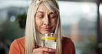 Kitchen, drink and woman with lemon in water for vitamin c, hydration and digestion benefits. Morning, antioxidant and mature person with citrus fruit for gut health, wellness and minerals for detox