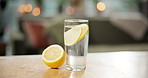 Kitchen, glass and water with lemon in home for vitamin c, hydration and digestion benefits. Empty, counter and fruit in liquid for gut health, wellness and minerals with citrus for antioxidant detox