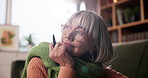 Senior woman, thinking and home with writer for story, copywriting or journalism by sofa. Elderly, female person or author in contemplation with novel for fantasy, imagination or literature in house