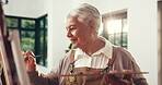 Painting, woman and creative in home, talent or artist with paintbrush for artwork, smile and craft. Happy, elderly person and inspiration for project, canvas and process with watercolor in lounge