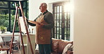 Elderly man, artist or painting with canvas in home for art, hobby or creative activity. Senior, male person or painter with brush on easel for artistic creation or artwork talent in retirement house