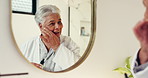 Senior woman, serum and bathroom with mirror for skincare, facial treatment or cosmetics in home. Happy, elderly or female person with smile or reflection for beauty, vitamin C oil or anti aging