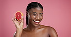 Skincare, face and black woman in studio with grapefruit for face hydration, glow or treatment. Beauty, smile and African female person with citrus fruit for facial dermatology by pink background.