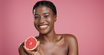 Skincare, happy and face of black woman in studio with grapefruit for hydration, glow or treatment. Beauty, smile and African female person with citrus fruit for facial dermatology by pink background