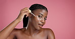 Face, skincare and black woman with serum for beauty, hyaluronic acid and vitamin c. Portrait, happy model and dropper for cosmetic, apply collagen and oil for dermatology on pink studio background