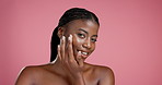 Face, black woman and apply lotion for skincare, hydration or collagen treatment for dermatology. Portrait, happy model and cream for cosmetics, beauty or moisturizer on pink studio background space