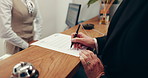 Hands, woman and signature at reception in hotel for check in, registration or hospitality service. Pen, paper and sign with client at motel for reservation confirmation, travel or accommodation form