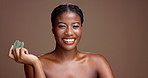 Woman, gua sha and face in studio for beauty, circulation and skincare with product by background. African girl, model and happy for stone tools, portrait or mock up space for dermatology in Nigeria