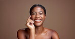 Beauty, skincare and touch with face of black woman in studio for dermatology, grooming and self care. Glow, happiness and shine with person on brown background for collagen, hydration and space