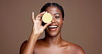 Eye, cover or happy black woman with lemon for brightening, beauty or space. Brown background, healthy glow or African model in studio with tropical citrus for detox benefits, vitamin c or skincare