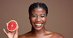 Laugh, face or African model in studio with grapefruit for brightening, beauty or space. Portrait, smile or happy black woman on brown background with tropical citrus for glow, vitamin c or skincare