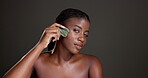 Gua sha, beauty and face of black woman in studio for lymphatic drainage, skincare and detox. Facial tools, glow and collagen with person on dark background for massage and holistic treatment 