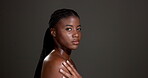 Face, bodycare and woman with glow, studio or healthy skin with cosmetics, confident or dermatology. Gray background, black person and pride for shine, soft and self care with treatment and wellness