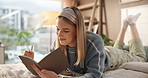 Woman, writing and lying with book in bed for story, schedule reminder or diary in home. Female person, freelancer or journalist taking notes in bedroom for new novel, ideas or inspiration in house