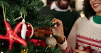 Christmas, tree and couple hang ornament in home for holiday, festive tradition and bonding. Relationship, love and happy man and woman with bauble for celebration, December and xmas aesthetic