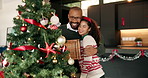 Christmas, tree and couple with ornament in home for holiday, festive tradition and bonding. Relationship, love and happy man hug woman with bauble for celebration, December and xmas aesthetic