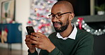 Smile, black man and phone at house on Christmas for social media, browsing web and gift search. Male person, laughing or mobile for funny message, online shopping and reading meme of festive season
