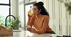 Woman, smartphone and orange juice in kitchen with texting, communication or typing in chat on social media. Reading, blog and drink with mobile app, share post or notification with smile at home