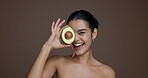 Face, skincare and woman with avocado, glow and natural cosmetic for anti aging, smile and wellness. Studio background, happy and person with fruit for dermatology, mockup space or treatment for skin