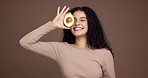 Skincare, woman and face in studio with avocado, brown background and playful attitude. Space, happy and female model with beauty glow, laugh and self care with natural, organic or facial cosmetics