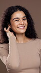 Smile, curly hair and face of woman in studio for beauty, salon transformation and self care. Natural texture, glow and keratin shine with female model on brown background for growth and shampoo