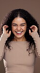 Shake, curly hair and smile with face of woman in studio for beauty, salon transformation and self care. Natural texture, glow and keratin shine with model on brown background for growth and shampoo