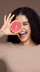 Skincare, grapefruit and face of woman in studio for natural, health and facial glow with hydration. Organic, happy and portrait of female person with citrus fruit for brightening by brown background