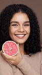 Grapefruit, beauty and face of woman in studio for skincare, natural cosmetics and facial care. Brown background, dermatology and portrait of person with fruit for vitamins, organic benefits and glow