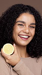 Health, lemon and face of woman in studio for natural, skincare and facial glow with hydration. Organic, happy and portrait of female person with citrus fruit for brightening by brown background.